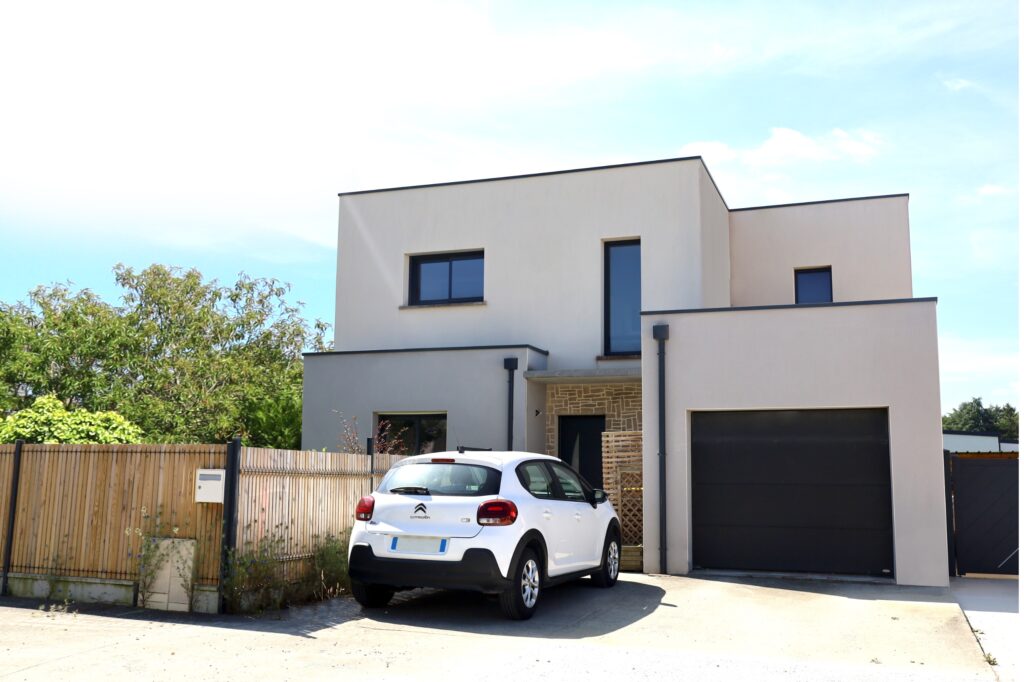 Maison d'architecte blanche avec une voiture blanche garée devant le garage